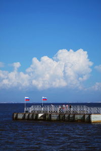 Russian flags on pier over sea against sky