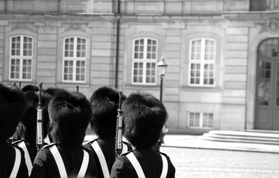 Rear view of army soldiers standing on street against building