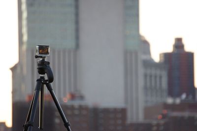 Close-up of camera against modern buildings in city