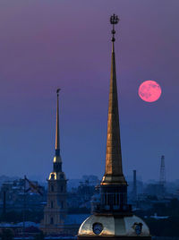 Towers in city against sky during sunset