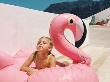 Girl relaxing on inflatable ring in swan shape during sunny day