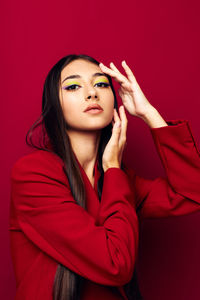 Portrait of young woman against red background