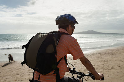 Rear view of man with bicycle on beach