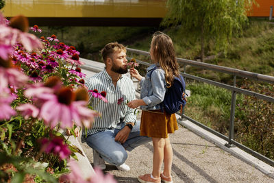 Father smelling flower held by daughter