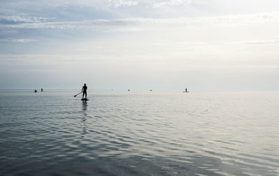 Young man on stand up paddle board on sea on sunny summer day, active lifestyle, outdoor activity