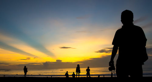 Silhouette people on beach during sunset