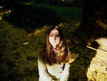 Portrait of beautiful young woman standing against trees