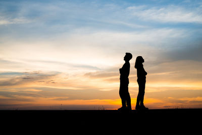 Silhouette man and woman standing against sky