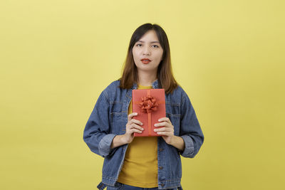 Portrait of beautiful woman standing against yellow background