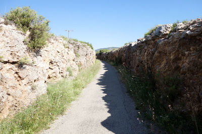 Road amidst rocks against clear sky