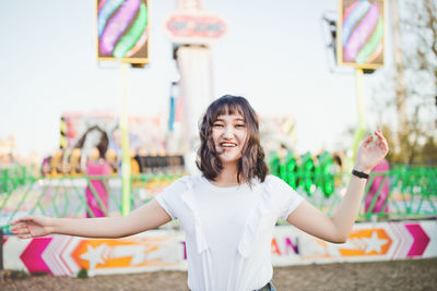 Beautiful young asian millennial girl in an amusement park, smiling. copy space.