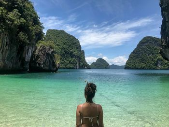 Rear view of woman standing in sea against sky