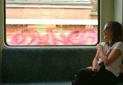 Cheerful woman sitting by window in train 