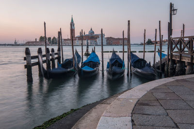 Isola di san giorgio maggiore seen from marcus place at sunrise with lot of gondolas in foreground.