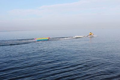 Man riding jet boat in sea against sky