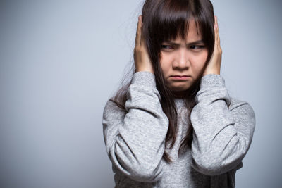 Young woman standing against gray background