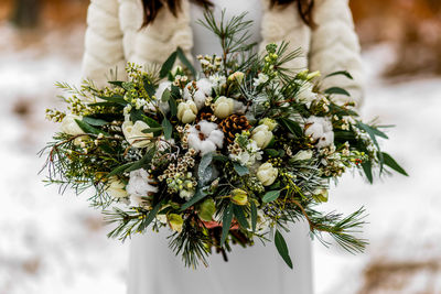 Midsection of woman holding bouquet during winter