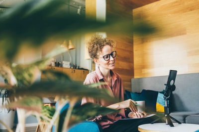 Portrait of young woman using mobile phone while sitting in cafe