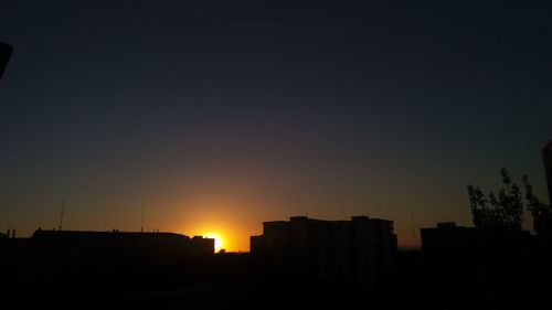 Silhouette of buildings against clear sky at sunset