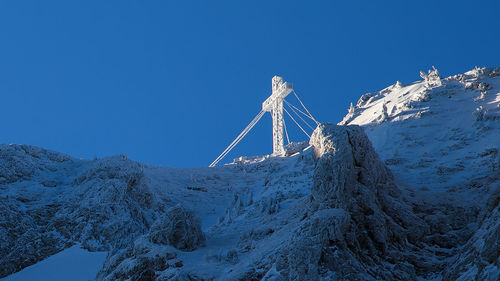 Low angle view of snowcapped mountain against blue sky