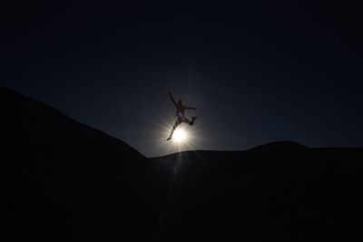 Low angle view of silhouette airplane flying against sky at sunset