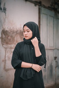 Young woman standing against wall