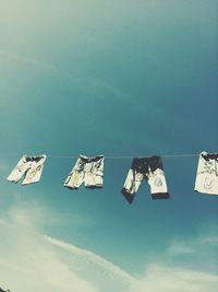 Low angle view of pants hanging on clothesline against sky