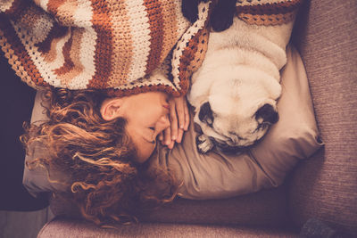 Directly above shot of woman sleeping with dog on sofa at home