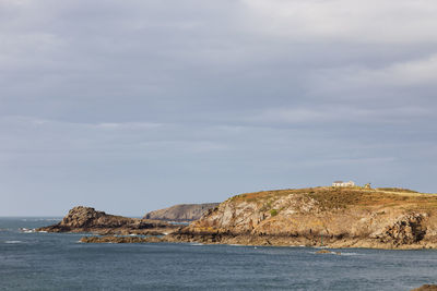 Scenic view of sea and cliff against sky