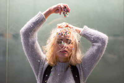 Portrait of beautiful woman holding confetti indoors