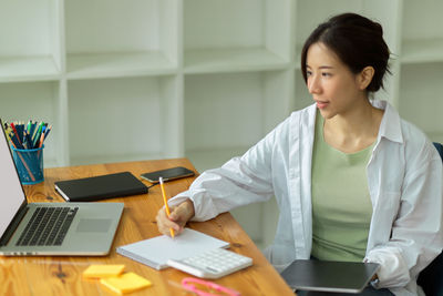 Mid adult woman using smart phone while sitting on table