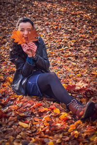 Man sitting on maple leaves during autumn