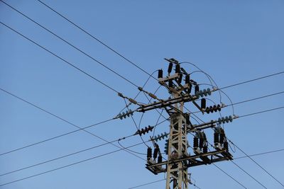 Low angle view of electricity pylon against clear sky