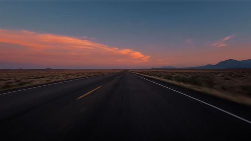 Empty road along landscape at sunset