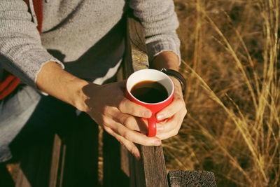 Midsection of man holding coffee cup