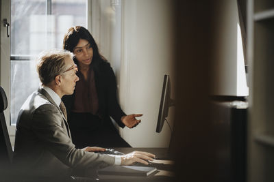 Female entrepreneur explaining businessman using computer at office