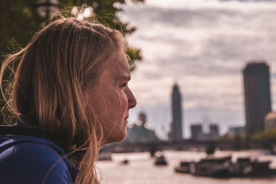 Profile view of young woman against river in city