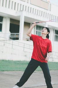 Young woman playing badminton while standing outdoors