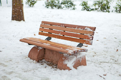 Close-up of empty bench on snow covered field