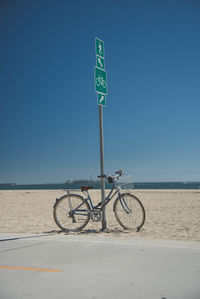 Bicycle sign on beach against clear blue sky