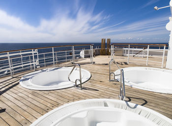 Chairs and table by sea against sky