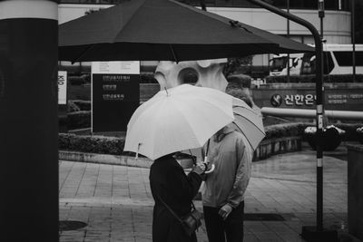 Rear view of people walking on street during rainy season