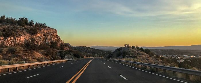 Road leading towards city against sky