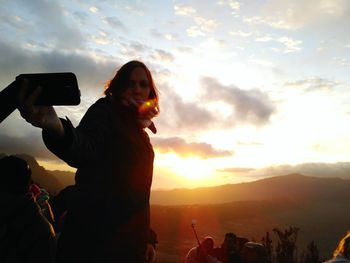 Woman photographing at sunset