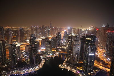 Illuminated buildings in city against sky at night