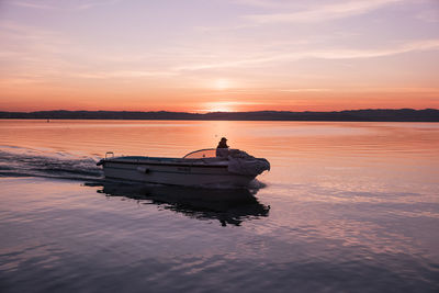 Boat on sea against sky during sunset