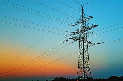 Low angle view of silhouette electricity pylon against sky during sunset