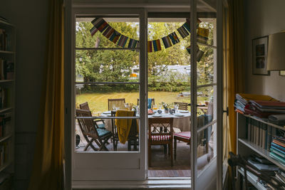 Chairs and tables arranged in back yard seen through doorway