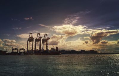 Panoramic view of factory by sea against sky