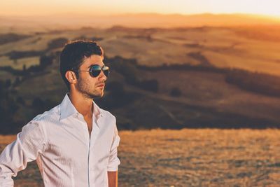 Midsection of man with camera on field during sunset